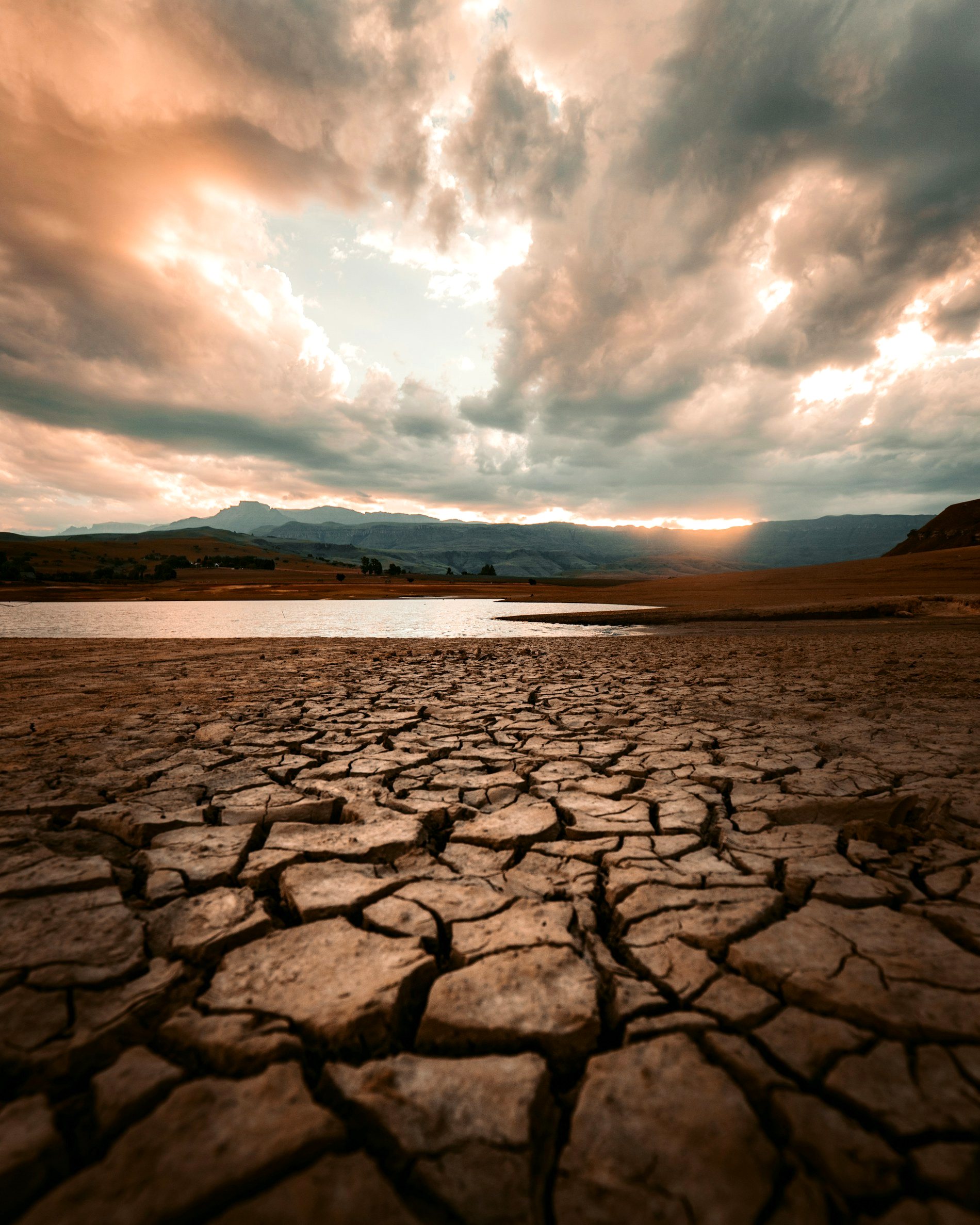 Cracked, drought stricken earth beside a shrinking reservoir